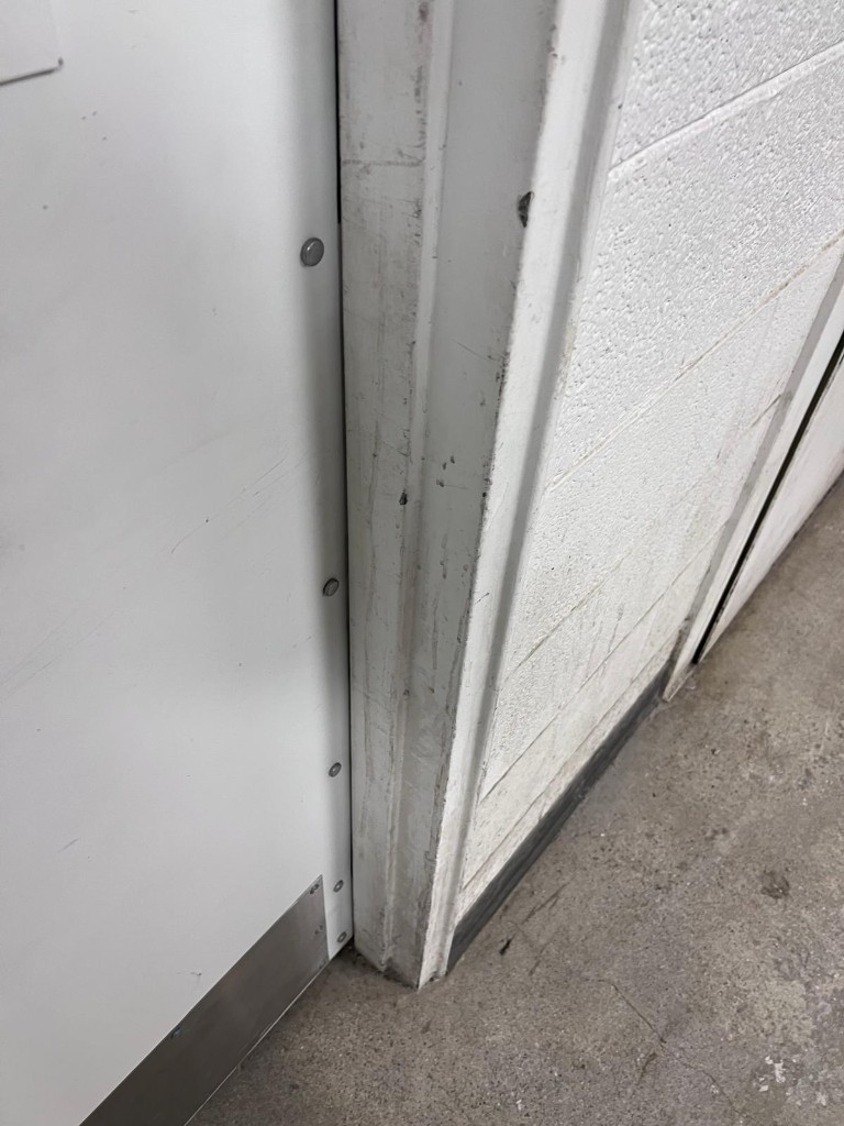 Commercial door frame and surround before service — no people. Reference photo 1 of 1.